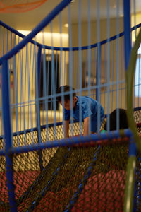 Full length of young man sitting on metal fence