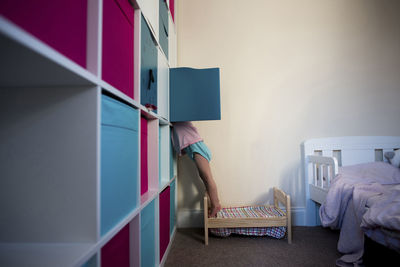 Low section of girl checking cabinet at home