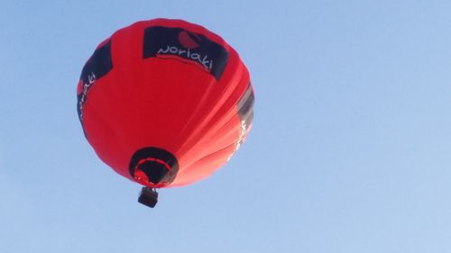 Low angle view of red balloon against clear blue sky