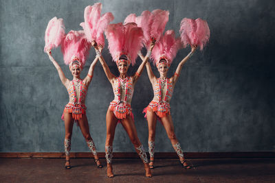 Full length portrait of woman dancing against wall