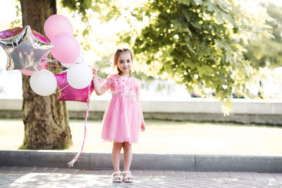 Full length of young woman with arms raised standing in park