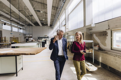 Businessman explaining colleague walking in factory