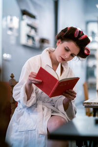 Young woman reading book on table