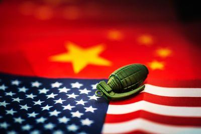 Close-up of grenade on american and chinese flag at table