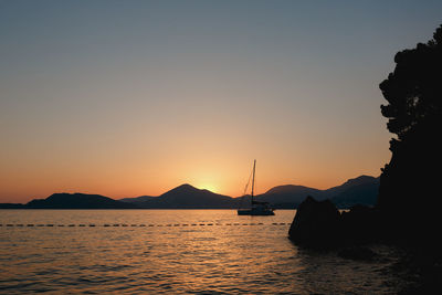 Silhouette sailboats in sea against sky during sunset