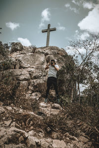 Man photographing while standing on cliff against sky