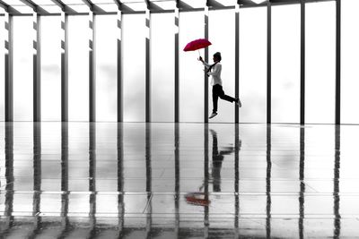 Side view of man with umbrella jumping against window