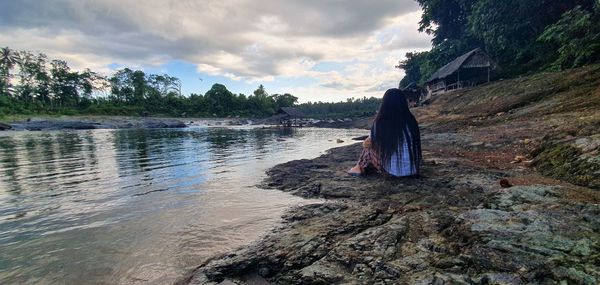Rear view of woman on rock against sky