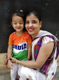 Portrait of happy mother and daughter against wall