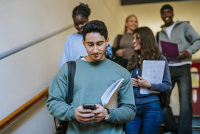Side view of man using mobile phone while sitting on sofa at home