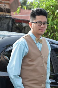 Portrait of young man standing by car