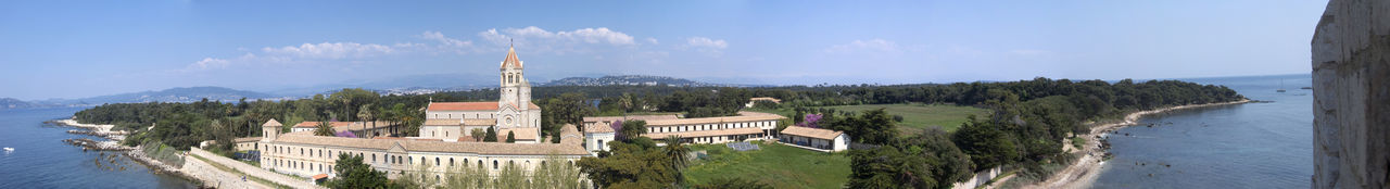 Panoramic view of buildings and trees against sky