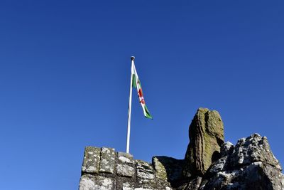 Low angle view of flag against clear blue sky