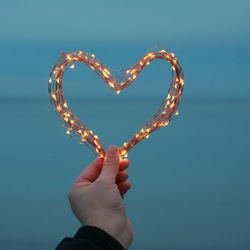 Close-up of hand holding illuminated heart shape