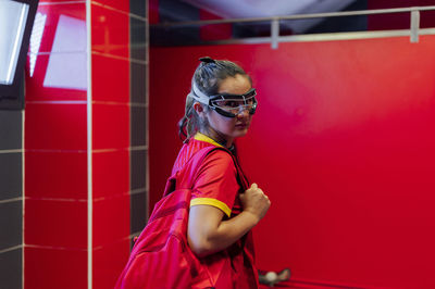 Lacrosse player with backpack standing in locker room