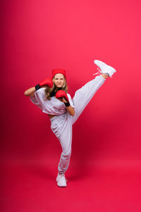 Full length of woman with arms raised standing against yellow background