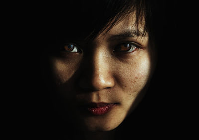 Portrait of young woman against black background