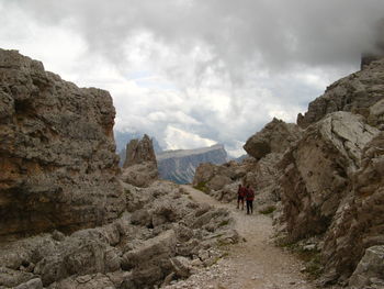 Rear view of people on rock formations against sky