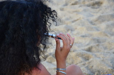 Close-up of woman smoking electronic cigarette at beach