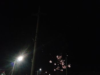 Low angle view of illuminated street lights against sky at night