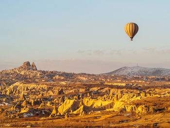 View of hot air balloon flying over landscape against sky during sunset