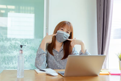 Portrait of woman using mobile phone while sitting on table