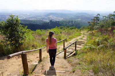 Rear view of woman walking on mountain against sky