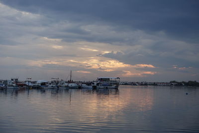 Boats moored at harbor against sky during sunset