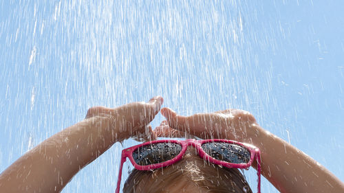 High section of girl in sunglasses under shower