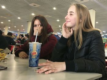 Young woman looking away while sitting on table in restaurant