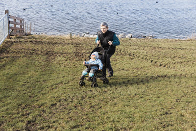 Grandfather with grandson walking against lake