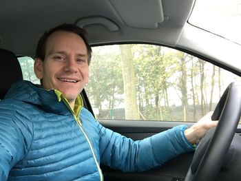 Portrait of smiling mid adult man sitting in car