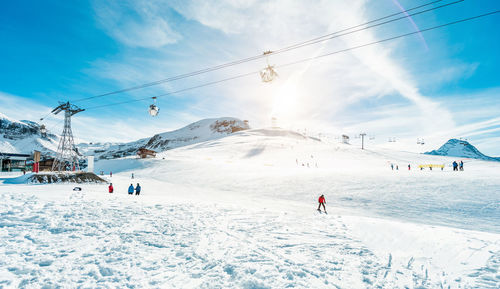 People skiing on snowcapped mountain against sky