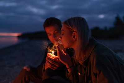 Young couple kissing against sky