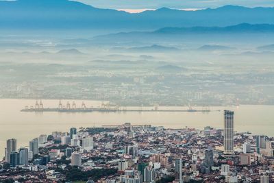 Aerial view of harbor by cityscape against sky