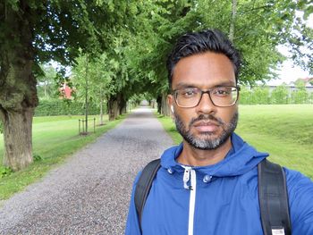 Portrait of man standing against trees in park