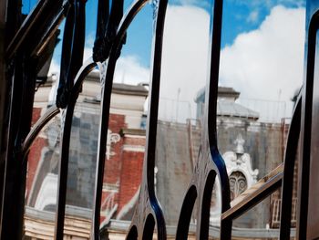 Low angle view of buildings reflecting on patterned glass window