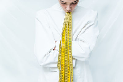 Midsection of man with yellow umbrella standing against white background