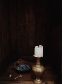 Close-up of illuminated lamp on table against wall