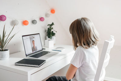 A teenage girl is talking to her dad or friend using a laptop. online communications. 