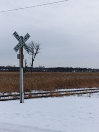 Road sign on field against sky during winter