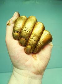 Close-up of man with golden paint against wall