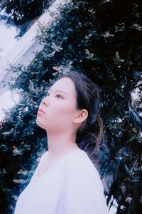 Thoughtful woman standing against trees