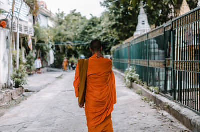 Rear view of monk walking on footpath