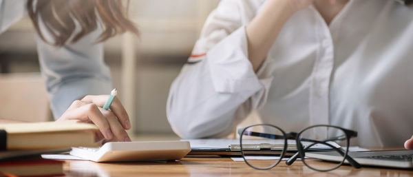 Midsection of woman reading book on table