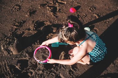 High angle view of girl playing with sand at beach