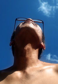 Low angle portrait of shirtless man against sky