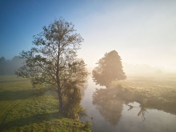 Autumn foggy sunrise. colorful misty morning dawn. fall rural scene. small river  trees meadow field