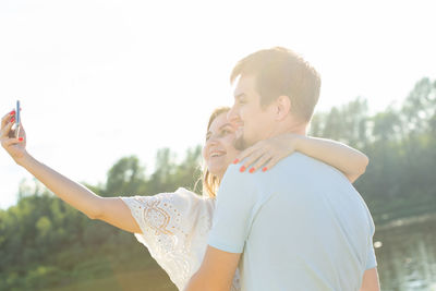 Rear view of man and woman standing on smart phone