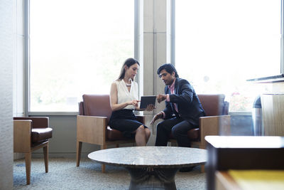 Colleagues discussing while using tablet computer in office